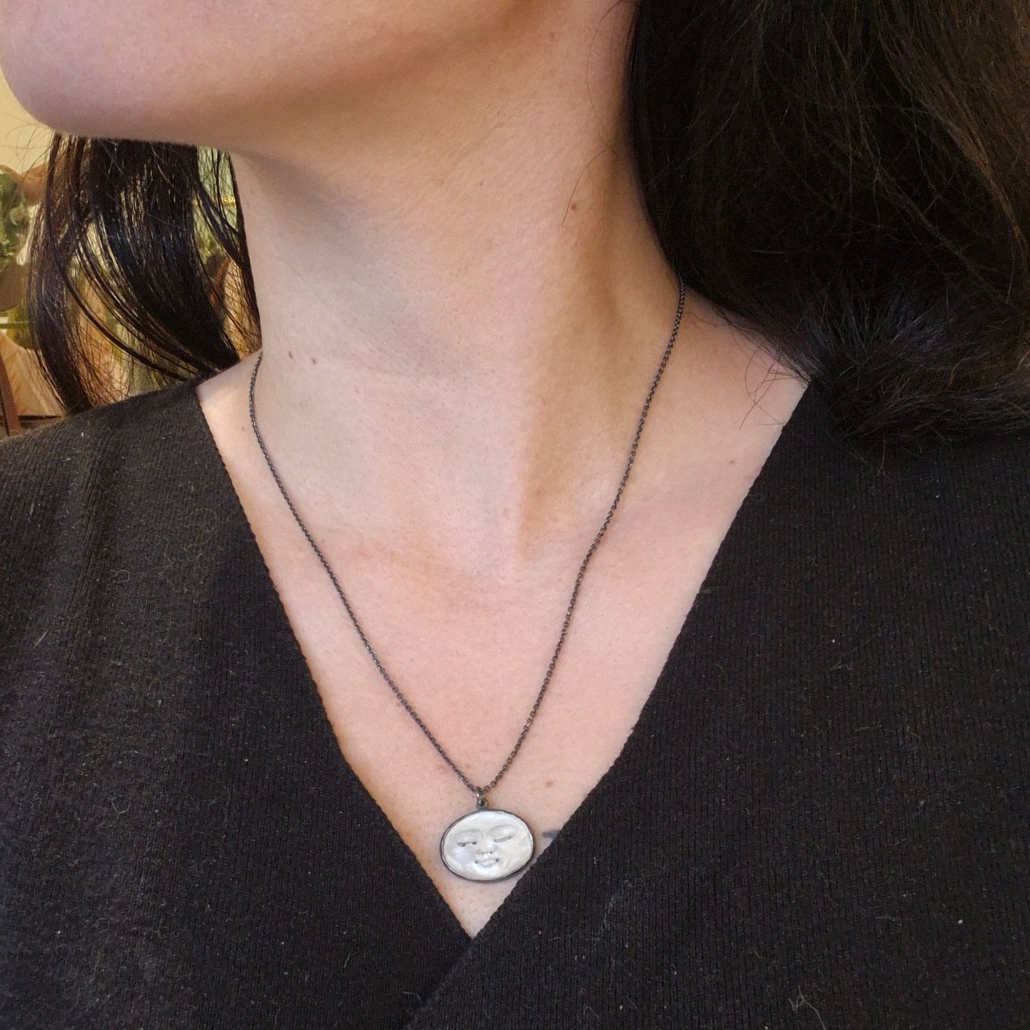 White moon face pendant on woman's neck by Alice Scott
