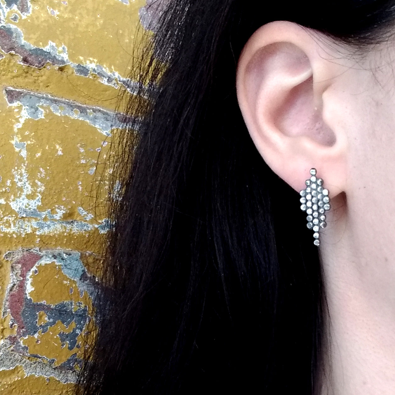 blackened silver dotted geometric post earrings on a model ear, by Alice Scott