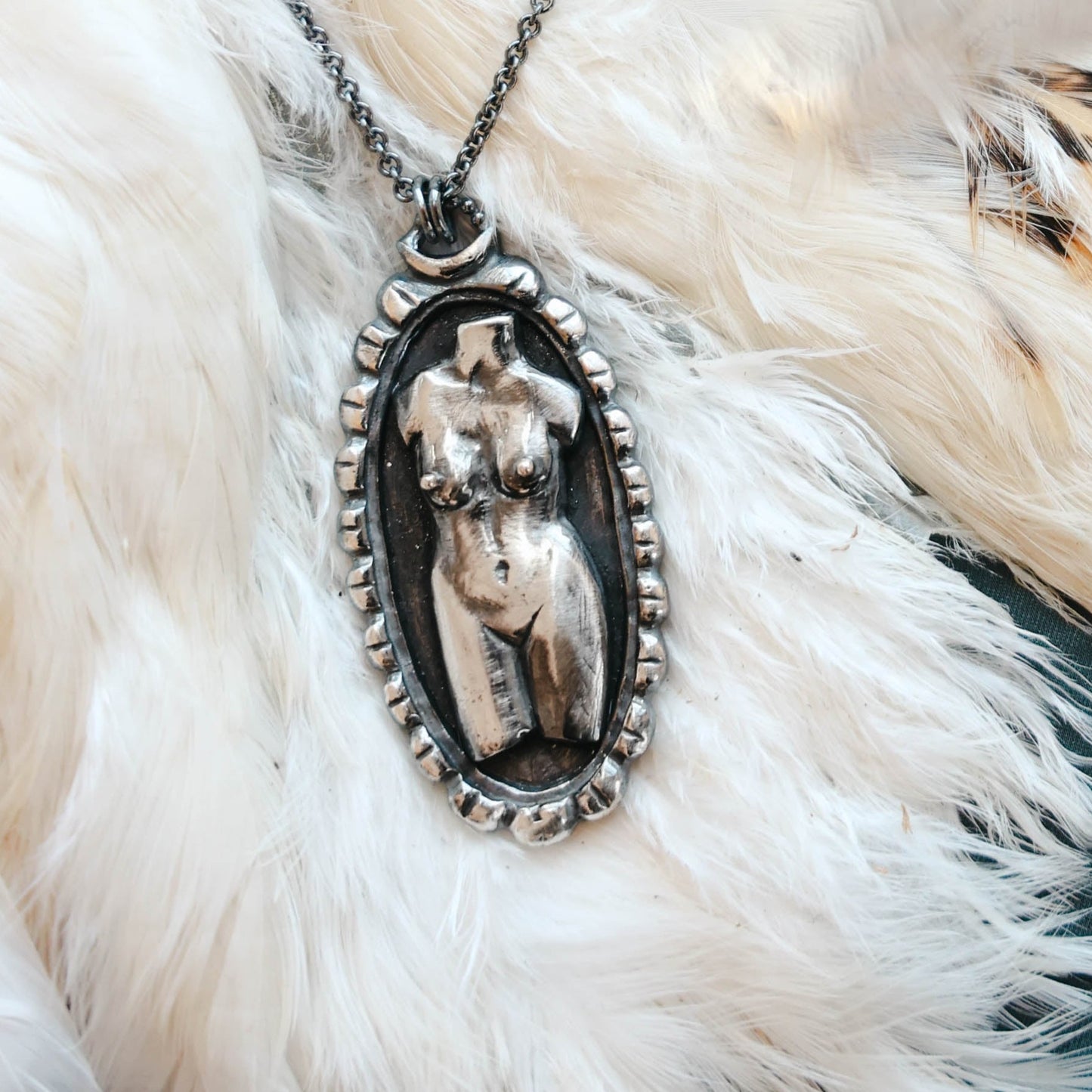 handmade Woman torso in sterling silver cameo pendant in sterling silver with black patina, on feather background, by Alice Scott