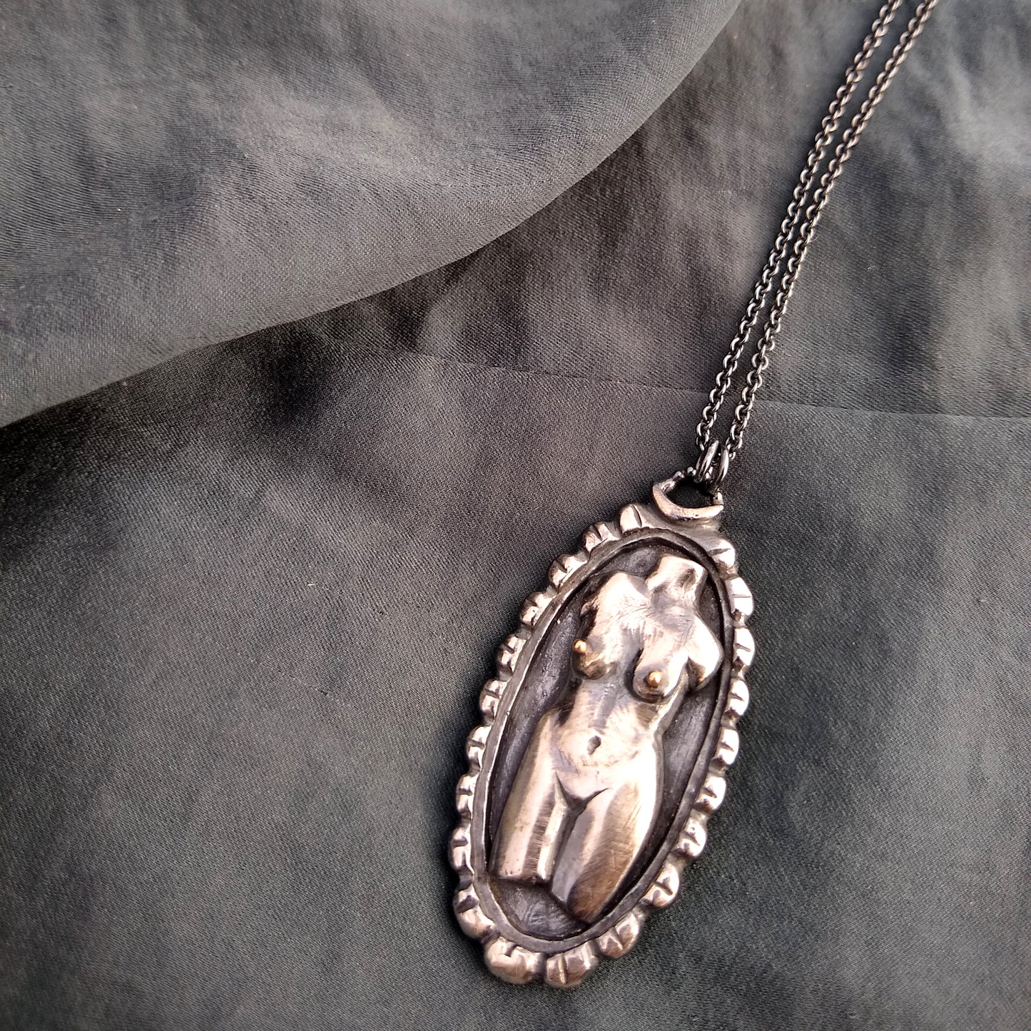 handmade Woman torso in sterling silver cameo pendant in sterling silver with black patina, on fabric background, by Alice Scott