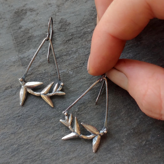 Silver cast Branch earrings with angle wires by Alice Scott on slate background and hand