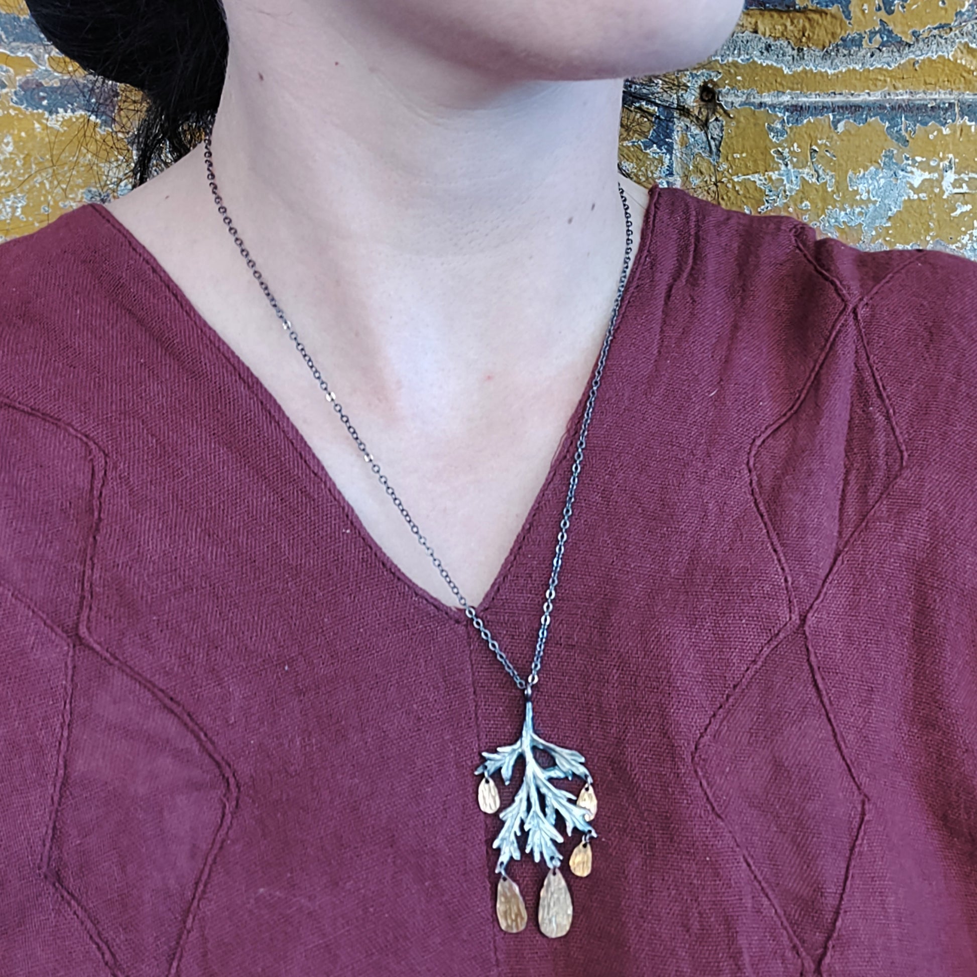 silver carved mugwort necklace with hammered gold fill drops by Alice Scott on a model neck