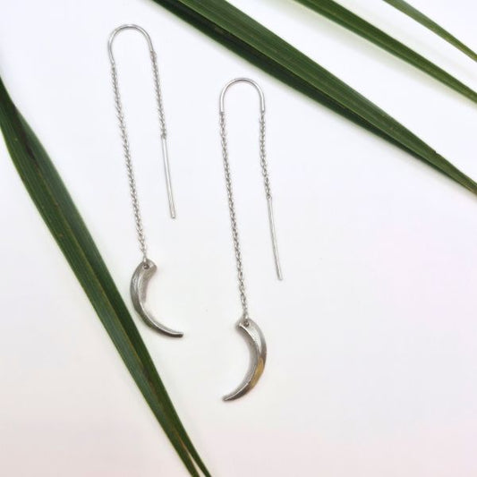 Silver claw earrings on a white background with green leaves by Alice Scott