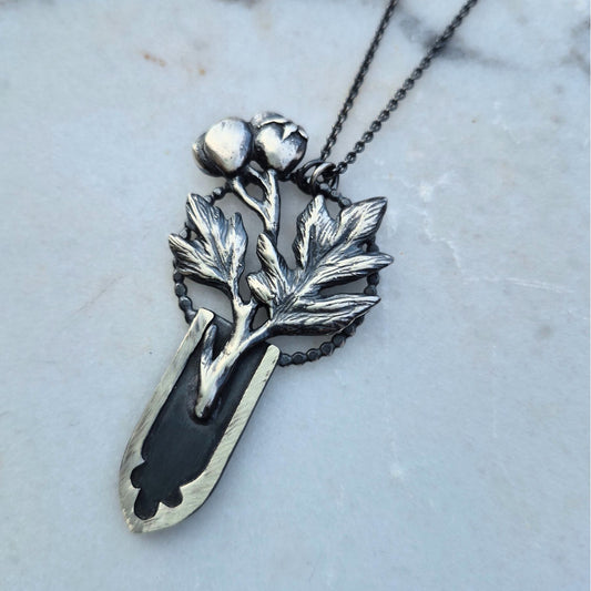 A silver necklace featuring a gothic arch design with a hawthorn branch growing from it, set against a marble background by Alice Scott