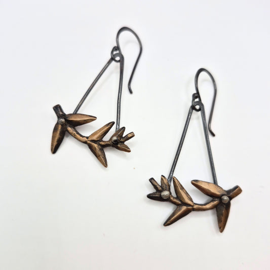 Pair of bronze leaf-shaped earrings on a white background by Alice Scott