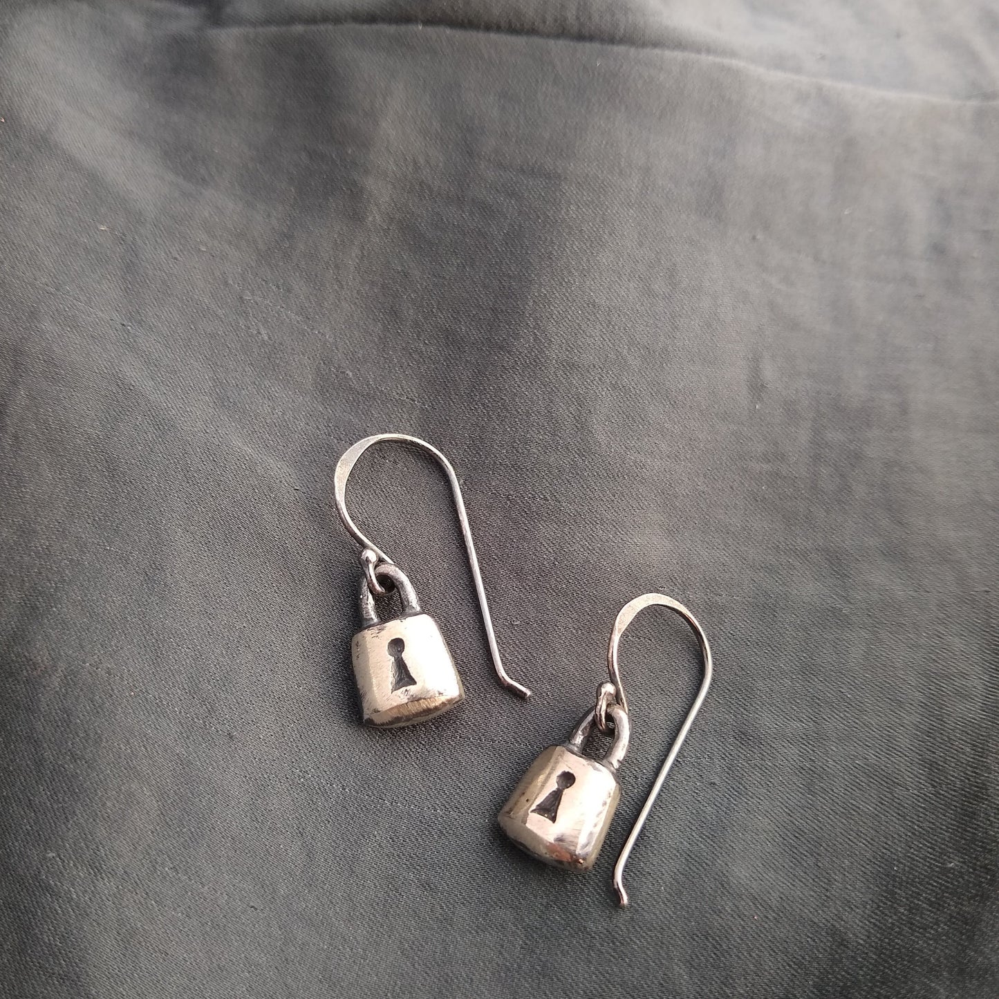 handmade padlock earrings in sterling silver with black patinas, on fabric background by Alice Scott