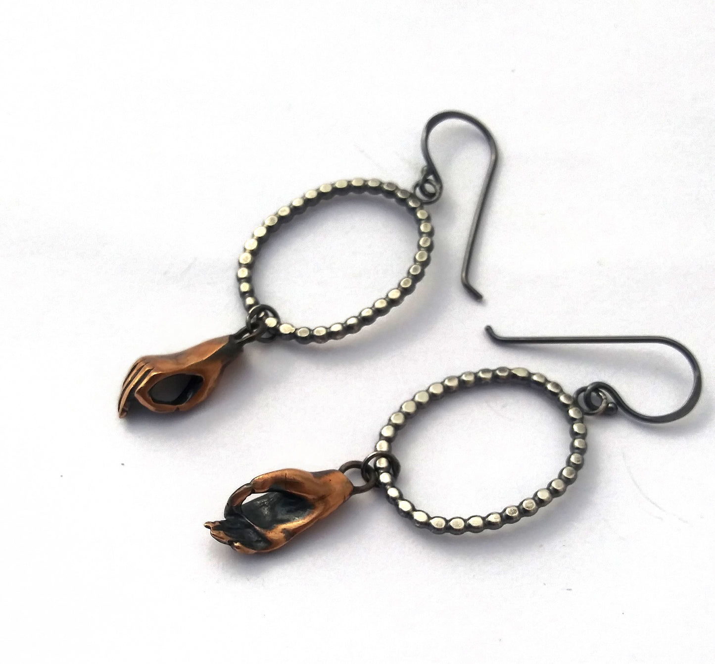 Dotted silver oval earrings with bronze cast meditating hands hanging, by Alice Scott on white background